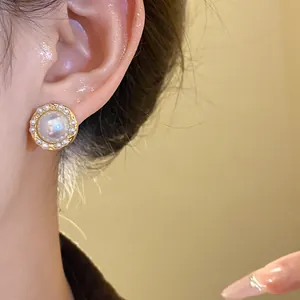 Close-up of elegant gold stud earring featuring central cat-eye stone and pearl halo