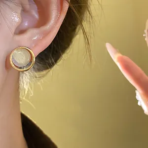 Detailed view of elegant gold geometric cat-eye stone stud earring worn on ear