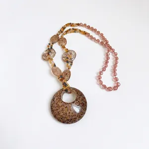Elegante collana bohémien con ciondolo in resina maculata su sfondo bianco puro.