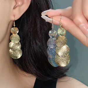 Primo piano di orecchini pendenti circolari opachi in oro e argento per donne
