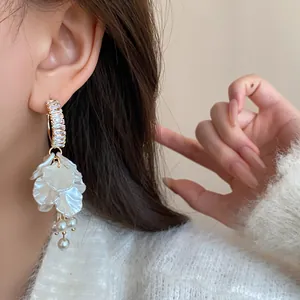 Detail shot of elegant white petal drop earrings with pearls and zircons for women.