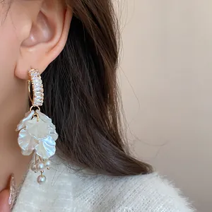 Close-up of elegant flower tassel earrings with zircon and pearls on model's ear