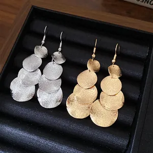 Vista dettagliata di orecchini a goccia con nappe tonde opache in oro e argento