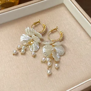 Elegant white petal tassel earrings with gold hoops and pearl details, close-up view.