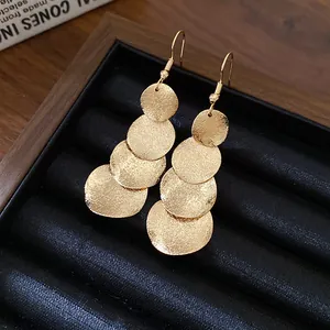 Vista dettagliata di eleganti orecchini pendenti in oro opaco con dischi rotondi