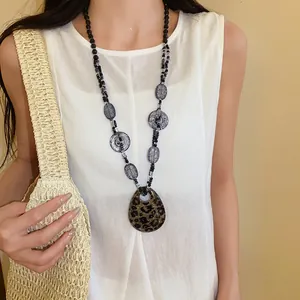 Dettaglio di una collana bohémien in resina con un elegante ciondolo a macchia leopardata
