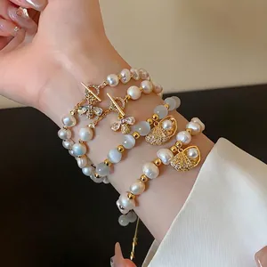 Elegant gold-plated pearl bracelet set with zircon bee and shell charms on wrist