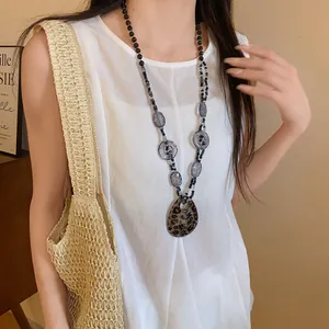 Dettaglio di una collana bohémien con ciondolo leopardato in resina su modella in bianco