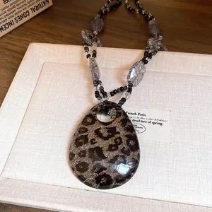 Primo piano di una collana bohémien in resina con ciondolo leopardato e perline.