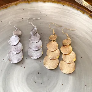 Dettaglio orecchini con nappa a dischi rotondi opachi in finitura oro e argento