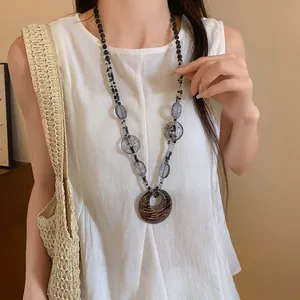Collana bohémien in resina con ciondolo leopardato indossata da una modella su top bianco