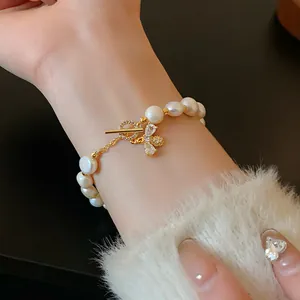 Elegant pearl bracelet featuring a sparkling gold bee charm worn on a female wrist