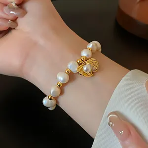 Macro view showing the elegant gold-plated shell pendant and pearls on a dainty bracelet