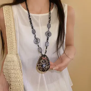 Dettaglio di una collana bohémien in resina leopardata indossata da una modella.
