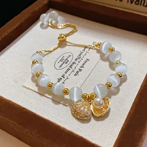 Close-up of elegant gold-plated cat's eye stone bracelet featuring shell and pearl charms