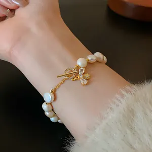 Close-up detail of a pearl bracelet with a gold-plated bee charm and zircon accents