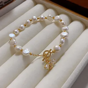 Detail view of elegant pearl bracelet featuring a sparkling zircon bee pendant and gold T-bar clasp