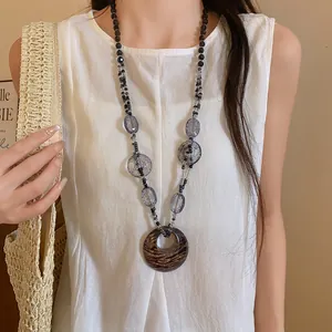 Dettaglio di una collana bohémien in resina con ciondolo leopardato chic su una modella