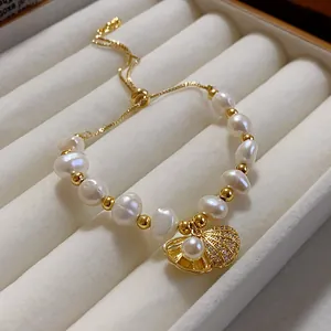 Close-up of elegant pearl bracelet with gold seashell charm displayed in a luxury jewelry box