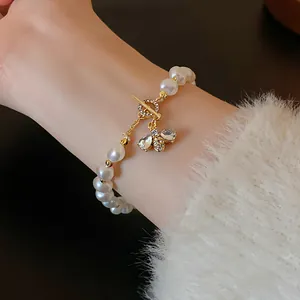 Close-up of retro pearl bracelet with gold bee charm and sparkling zircon stones.
