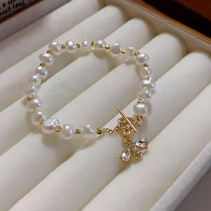 Close-up of retro pearl bracelet featuring a crystal-set bee pendant and toggle clasp