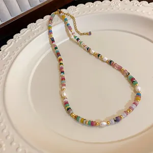 Gros plan d'un collier de perles colorées avec perles baroques sur une assiette blanche