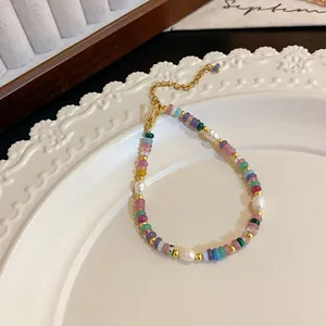 Gros plan d'un collier de perles baroques avec perles colorées sur assiette blanche