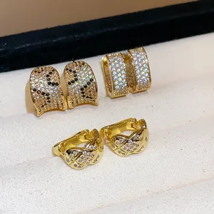 Close-up detail of three gold-plated zircon hoop earrings in heart and square shapes.