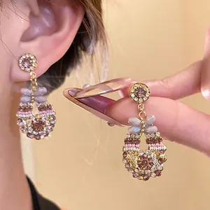 Nahaufnahme von Vintage-Ohrringen mit lila Kristallen und Schmetterlings-Detail.