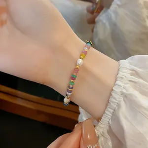Vue détaillée d'un bracelet de perles colorées porté au poignet d'un mannequin