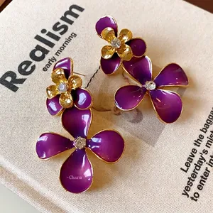 Vintage purple enamel flower earrings with gold finish and rhinestone centers.