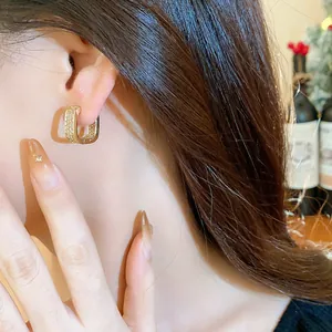 Close-up of elegant gold square hoop earrings with cubic zirconia inlay on model