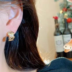 Close-up of a gold-plated square hoop earring with quilted texture and zircons