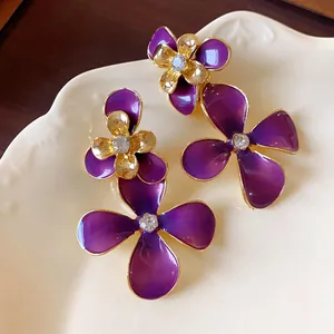 Detailed view of purple enamel flower earrings with gold trim and rhinestone centers