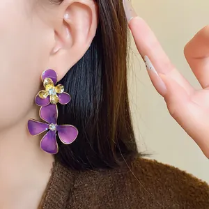 Close-up view of elegant long purple flower drop earrings with rhinestone centers