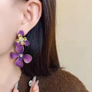 Close-up view of elegant purple enamel flower drop earrings worn by a fashion model