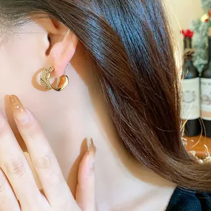 Close-up detail of 18k gold plated hoop earring with zircon texture on model's ear