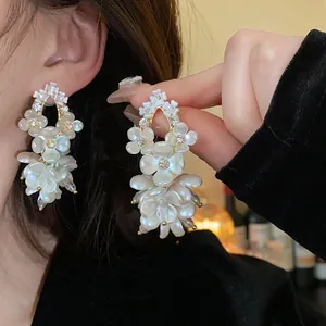 Macro detail of French vintage shell flower earrings with shimmering zircon accents.