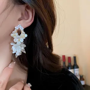 Detail showing elegant shell flower earrings with shimmering zirconia accents
