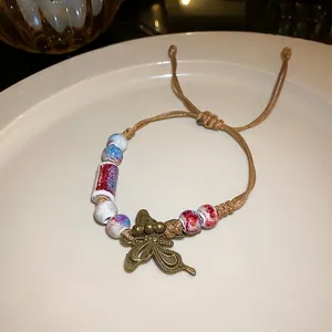 Handmade vintage butterfly charm bracelet featuring colorful ceramic beads and brown cord