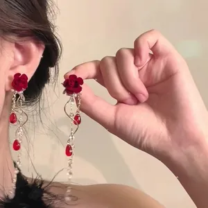 Detailed view of red rose earrings with long beaded tassels and pearls