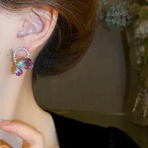 Detailed view of butterfly teardrop earrings with purple gradient crystals on ear.