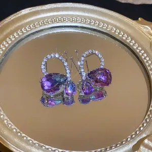 Detailed view of butterfly drop earrings featuring purple gradient stones and diamonds