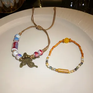 Detailed close-up of handmade ceramic butterfly braided bracelet and ethnic stone bead strand