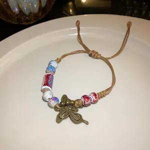 Detailed view of handmade ethnic braided rope bracelet with butterfly charm and ceramic beads