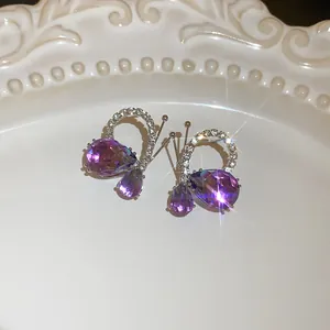 Close-up of butterfly earrings with purple teardrop crystals and sparkling rhinestones