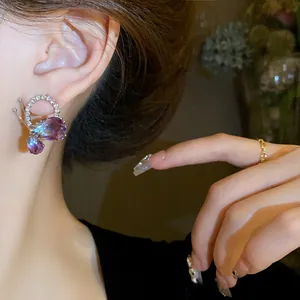 Detailed close-up view of elegant butterfly drop earrings with purple stones on the ear