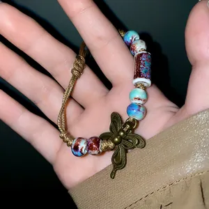 Close-up detail of ethnic ceramic bead bracelet featuring a bronze butterfly charm