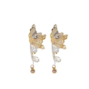 Eleganti orecchini a farfalla con cristalli, perni in argento e dettagli in perla.