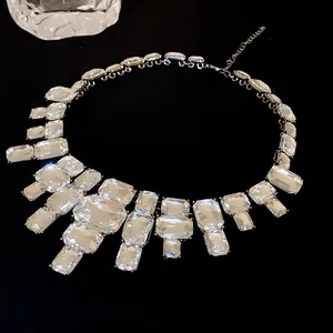 Detail of an exaggerated square crystal necklace with clear rhinestones on black background.